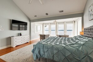 Quarto com uma cama grande, televisão de tela plana, penteadeira e vista para o exterior.
