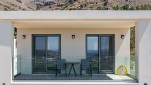 Ein moderner Balkon mit Glastrennwand, zwei Stühlen und einem Tisch.