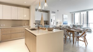 Una cocina moderna con una isla central, armarios de madera e iluminación colgante.