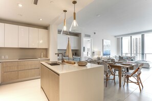 Una cocina moderna con una isla central, armarios de madera e iluminación colgante.