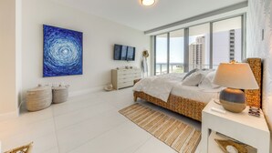 Un dormitorio moderno con una cama grande, televisión y vista a la ciudad desde la ventana.