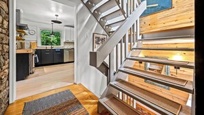 A modern kitchen with a wooden staircase leading to a loft area. - Luxe Mountain Home: Hot Tub, Sauna, Firepit, Games (Black Mountain)