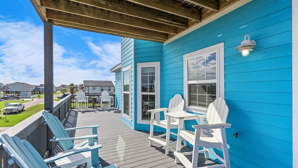 A covered deck with Adirondack chairs and a table, overlooking a residential area.