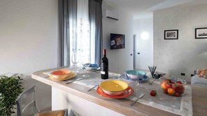 Een moderne keuken met een eettafel voor vier personen, met kleurrijke borden en een wijnfles.