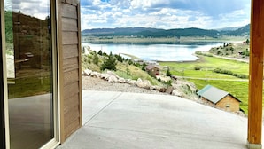 A covered outdoor area with a view of a lake and distant mountains.