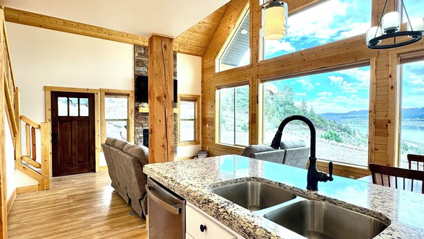 A spacious kitchen with granite countertops, a double sink, and large windows offering a view of the outdoors.