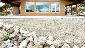 A modern building with a sloped roof, large windows, and wooden beams.