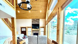 A spacious dining area with a wooden table and chairs, a ceiling fan, and a stone fireplace.