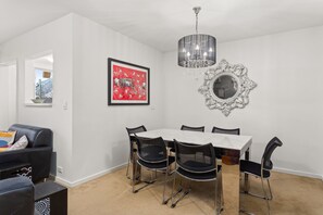 A dining area with a white table, black chairs, a chandelier, and a framed artwork on the wall. - Mama Koko Pet Friendly Retreat in Hawthorn East (Hawthorn East)
