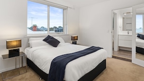 Une chambre moderne avec un grand lit, des lampes de chevet, une fenêtre et un miroir.