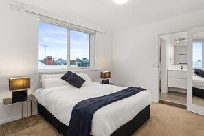 A modern bedroom with a large bed, bedside lamps, a window, and a mirror. - Mama Koko Pet Friendly Retreat in Hawthorn East (Hawthorn East)