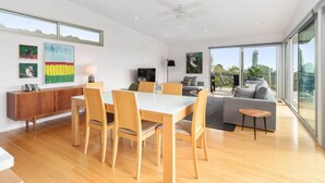 A modern living room with a dining area, large windows, and a balcony with a view.