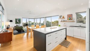 A modern kitchen with a central island, white cabinetry, and large windows.
