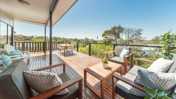 A wooden deck with outdoor seating, including a sofa and chairs, and a table.