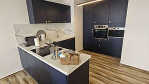Una cocina moderna con armarios oscuros, encimera de mármol y electrodomésticos integrados, como un microondas y un horno.
