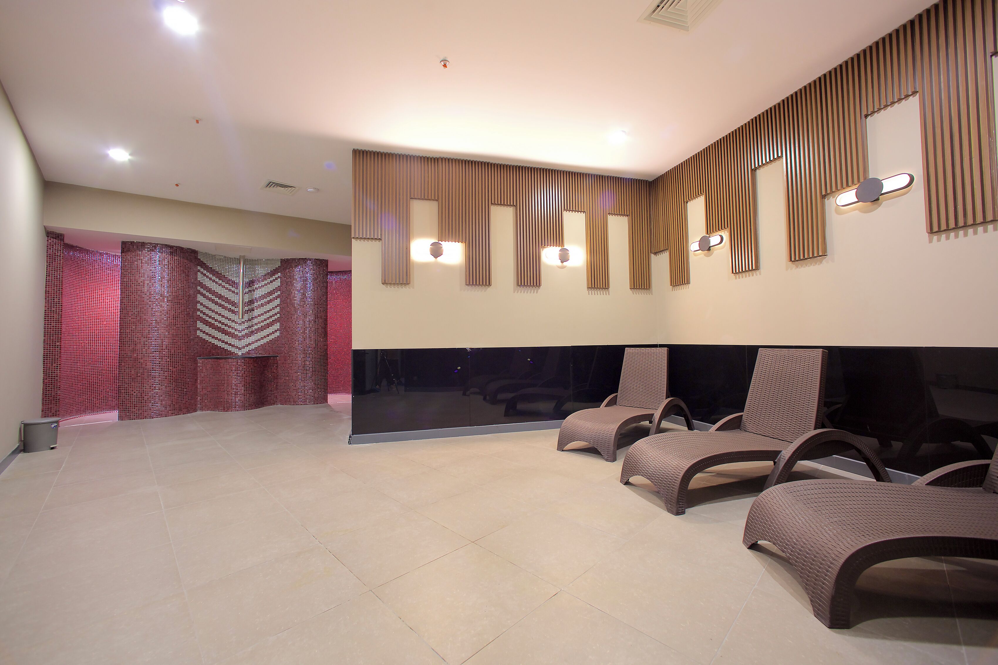A spacious room with a large mirror, two wicker chairs, and a tiled floor.