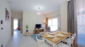 A modern living room with a dining area, a flat-screen TV, and a large window with curtains. - Best Western Plus Hotel & Residences Istanbul (Istanbul)