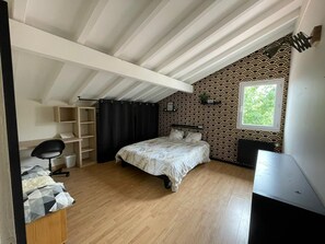 Een slaapkamer met een bed, een bureau, een stoel, een kledingkast en een raam.