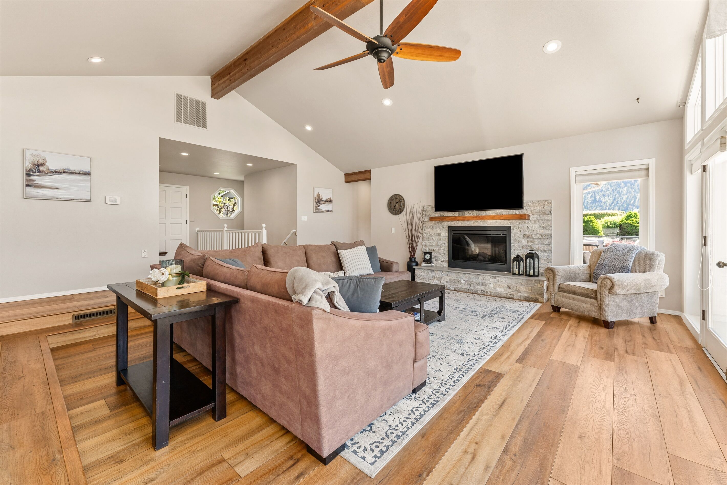 A spacious living room with a large sectional sofa, a fireplace, and a ceiling fan.