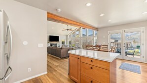 Een moderne keuken met houten kastjes, een groot eiland en een eethoek met uitzicht op de bergen.