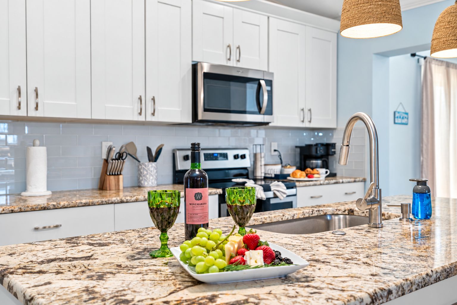 A modern kitchen with white cabinets, a stainless steel microwave, and a granite countertop.