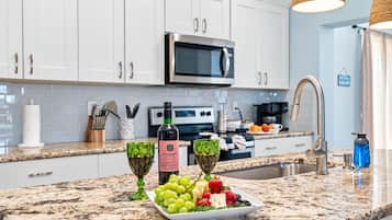 A modern kitchen with white cabinets, a stainless steel microwave, and a granite countertop.