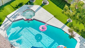 Une piscine avec un jacuzzi, un flotteur en forme de flamant rose et un flotteur en forme de licorne.