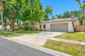A residential house with a garage, driveway, and well-maintained lawn. - Luxurious Spa Retreat with Stunning Pool in Palm Harbor (Palm Harbor)