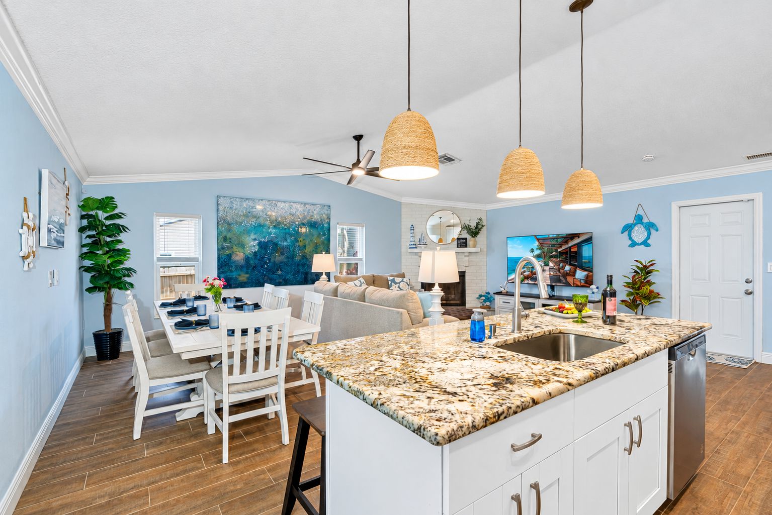 A modern kitchen with a granite countertop, white cabinetry, and a built-in dishwasher.