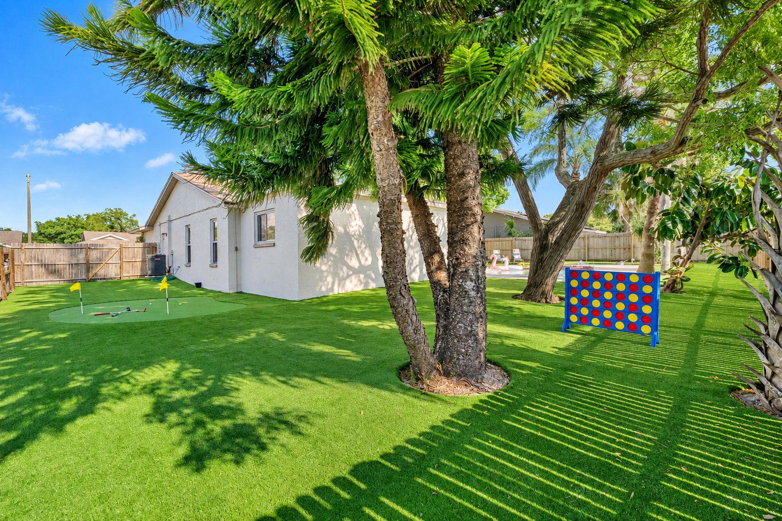 A backyard with artificial grass, a swing set, and a play area with a colorful board game.