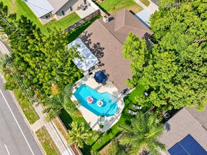Vista aérea de una propiedad residencial con piscina, rodeada de abundante vegetación y un patio cercado.