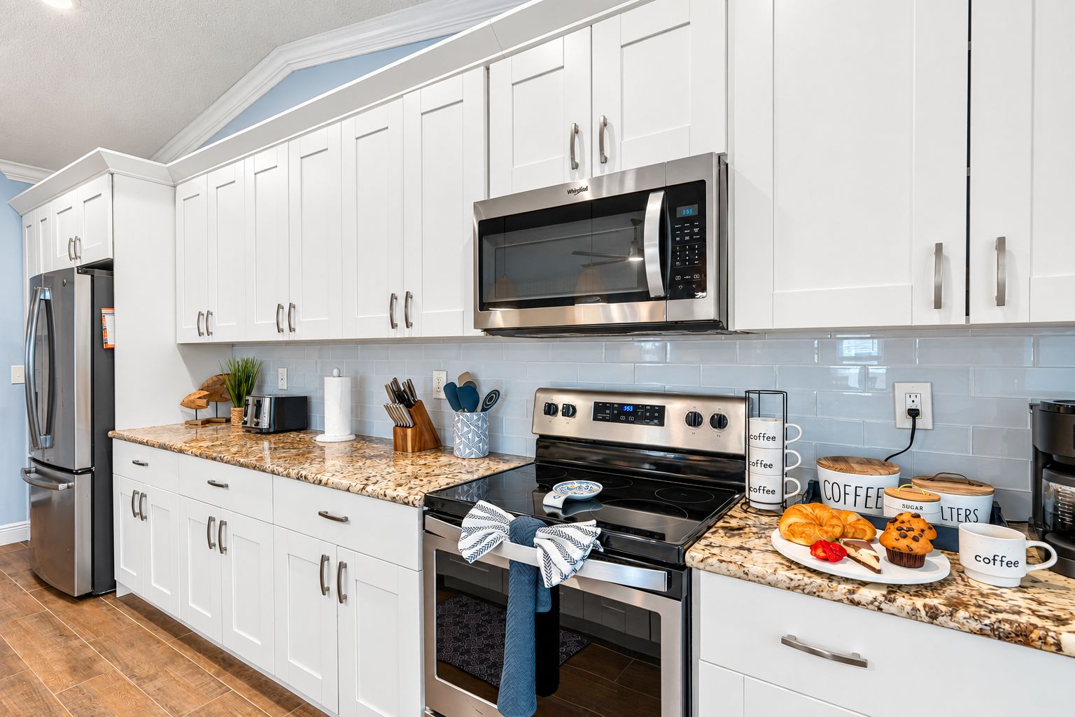 A modern kitchen with white cabinets, stainless steel appliances, and a granite countertop.