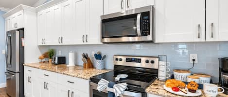 A modern kitchen with white cabinets, stainless steel appliances, and a granite countertop.