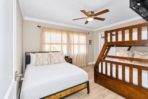 A bedroom with a bed, a wooden bunk bed, a ceiling fan, and a window with curtains. - Luxurious Spa Retreat with Stunning Pool in Palm Harbor (Palm Harbor)