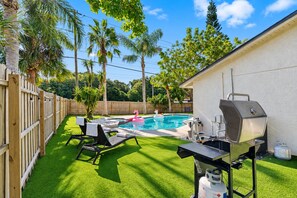 Ein Garten mit Pool, Grill und Holzzaun.
