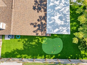 Une terrasse avec une zone pavée et un espace vert agrémenté de balles de golf et d’un drapeau.