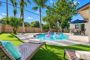 Ein Garten mit Swimmingpool, Liegestühlen und Essbereich.