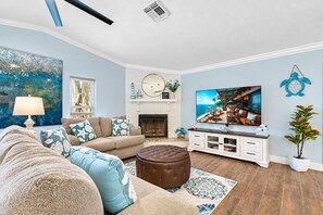 A living room with a sofa, ottoman, and a flat-screen TV. - Luxurious Spa Retreat with Stunning Pool in Palm Harbor (Palm Harbor)