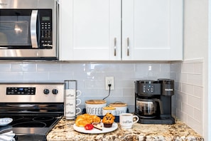 A kitchen with a microwave, coffee maker, and a plate of pastries. - Luxurious Spa Retreat with Stunning Pool in Palm Harbor (Palm Harbor)