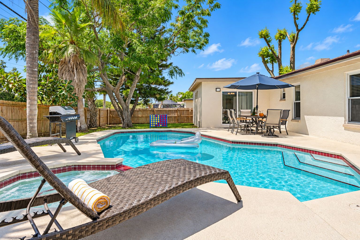 A backyard with a swimming pool, a grill, and a covered patio area.