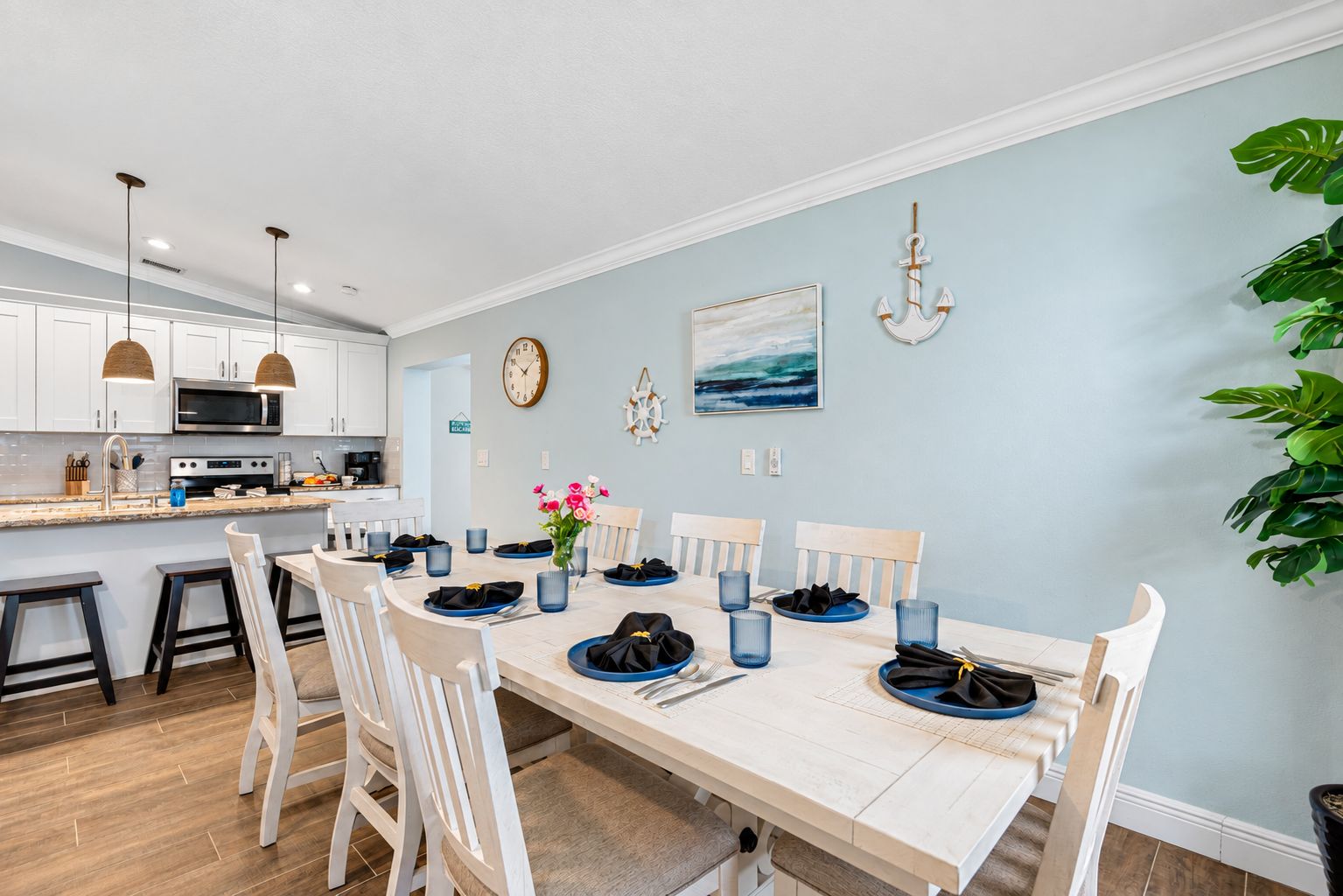 A dining area with a white table set for four, surrounded by white chairs.