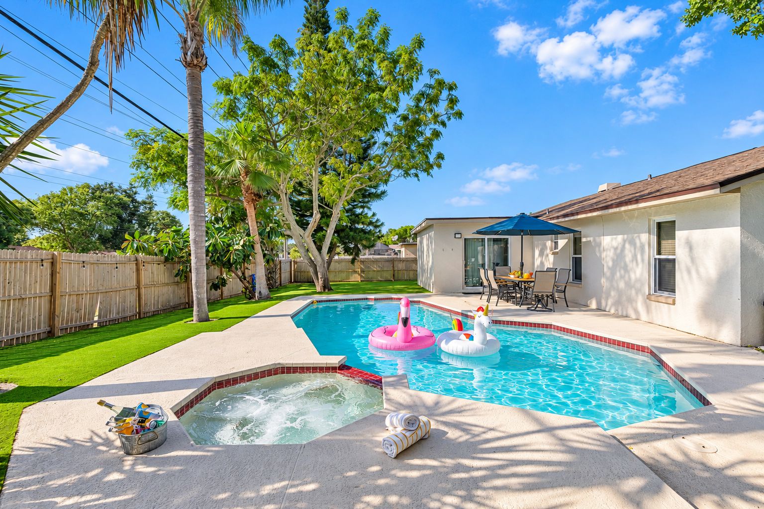 Un jardin avec une piscine, des jeux gonflables, un jacuzzi et un espace patio.