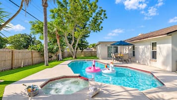 Un jardin avec une piscine, des jeux gonflables, un jacuzzi et un espace patio.