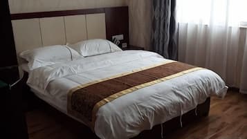A neatly made bed with a headboard, a bedside table, and a window with curtains.