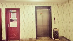 Un ascensor, una puerta con un aviso y un muro con diseño.