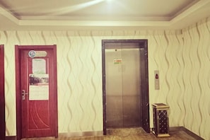 Un ascensor, una puerta con un aviso y un muro con diseño.