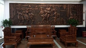 Un vestíbulo con una gran escultura de madera, un conjunto de sofás y dos plantas en macetas.