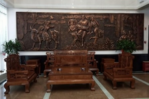 Un vestíbulo con una gran escultura de madera, un conjunto de sofás y dos plantas en macetas.