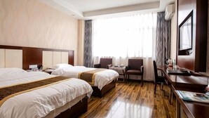 Habitación de hotel con dos camas, un escritorio, una silla y un televisor.