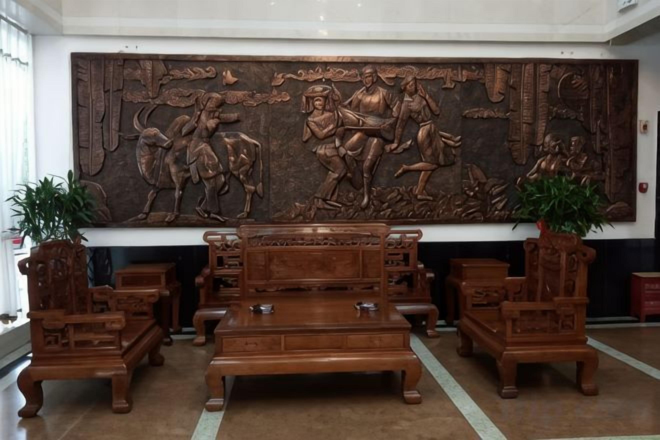 A lobby with a large wooden sculpture, a sofa set, and potted plants.